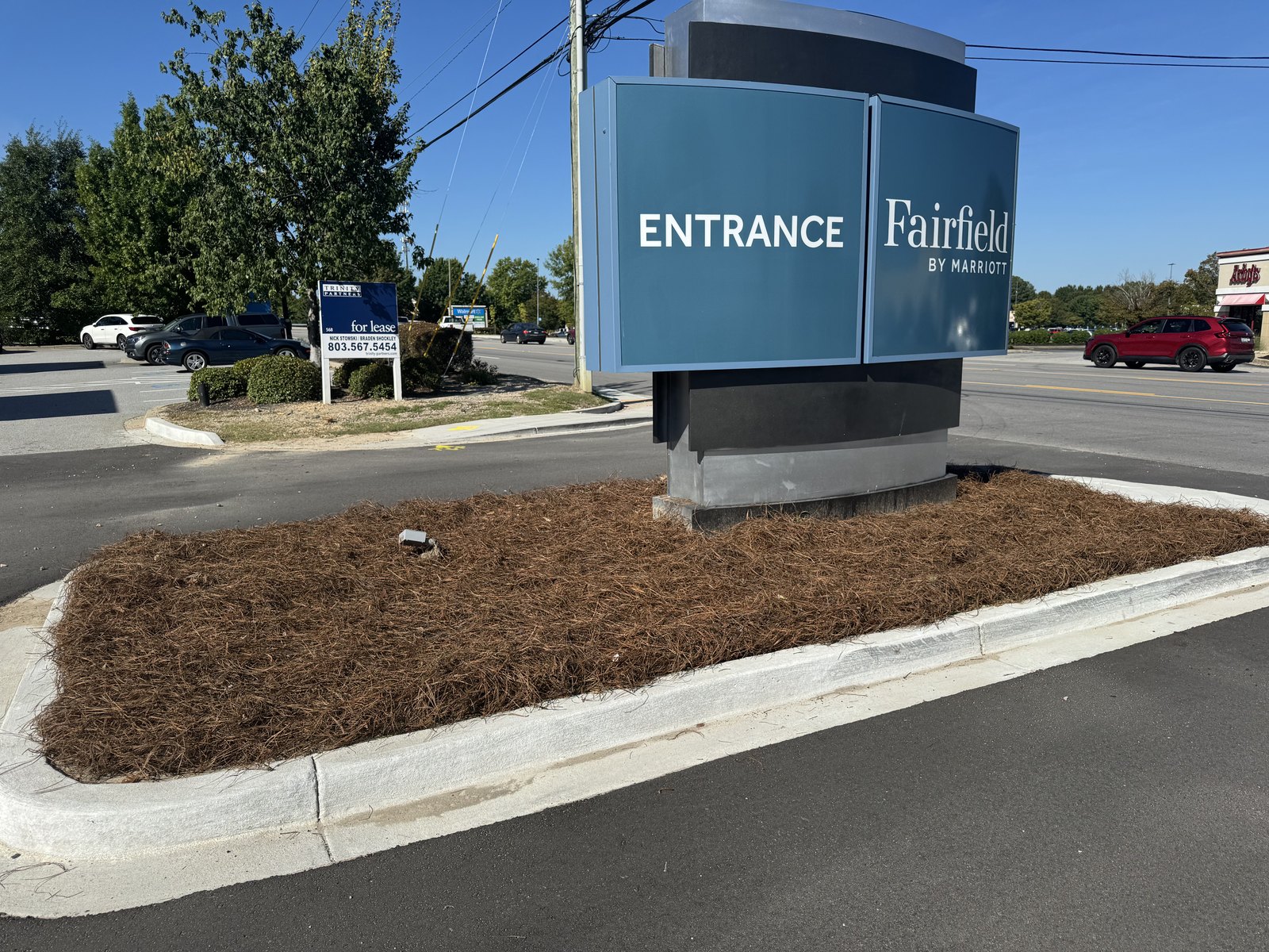 Freshly maintained landscape bed surrounding a commercial property entrance sign